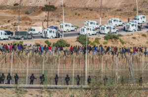 Migrants on a border fence separating Morocco from Melilla (Spain).